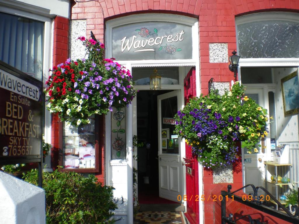 un edificio de ladrillo rojo con cestas de flores en la puerta en Wavecrest, en Holyhead
