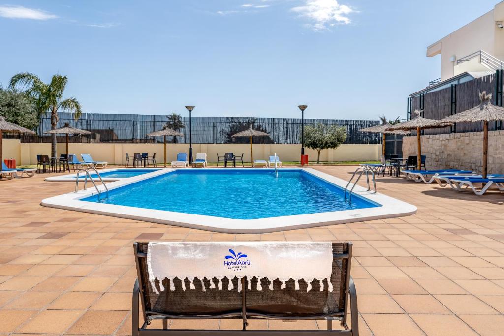 a pool at a hotel with a bench in the foreground at Hospedium Hotel Abril in San Juan de Alicante