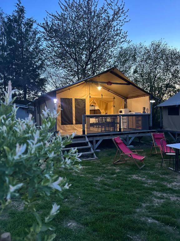 une maison avec une terrasse et des chaises dans la cour dans l'établissement Clos des Monts Tente Lodge Safari J, à Saint-Martin-des-Besaces