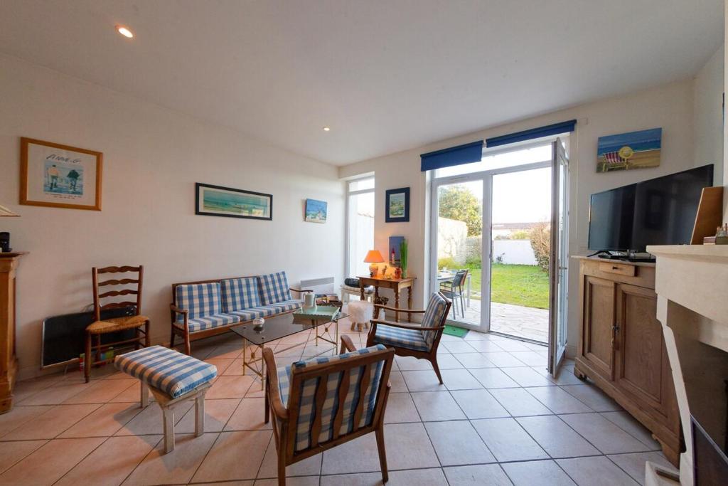 un salon avec une table, des chaises et une télévision dans l'établissement 022 Le petit clos, au Bois-Plage-en-Ré
