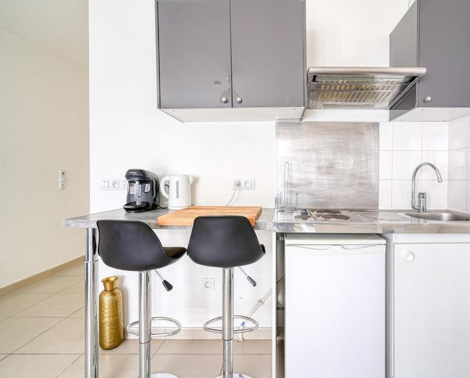 une cuisine avec deux tabourets de bar et un comptoir dans l'établissement À deux pas de Paris - Le Confidentiel - 8MB, à Issy-les-Moulineaux