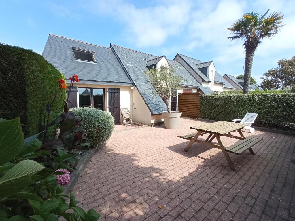 une terrasse avec une table de pique-nique en bois devant une maison dans l'établissement Brennick, Maison 4 pers proche mer et plage, à Clohars-Carnoët