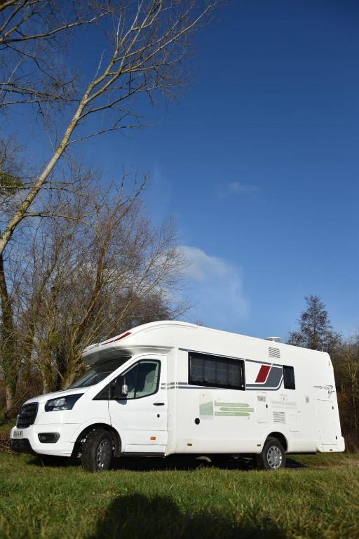 une camionnette blanche garée dans l'herbe dans un champ dans l'établissement CAMPING-CAR TOURISTIQUE du JURA, à Dole