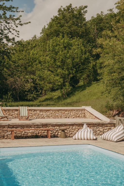 une piscine avec un banc et un mur en pierre dans l'établissement Maison proche de Paris, La Source, à Châlo-Saint-Mars