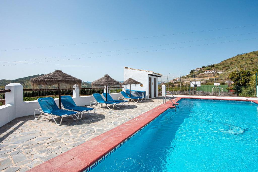 una piscina con sedie e ombrelloni blu di La Casa Grande a Málaga