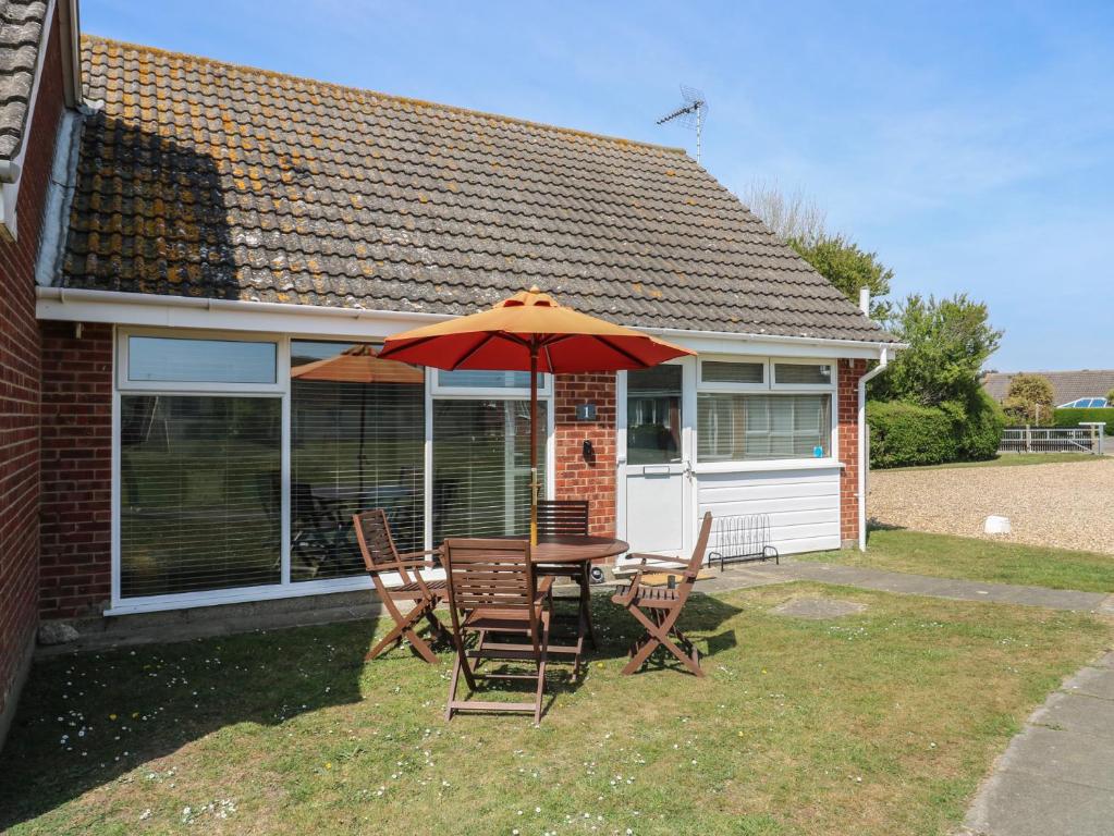 a table and chairs with an umbrella in front of a house at 1 Kessingland Cottages in Lowestoft