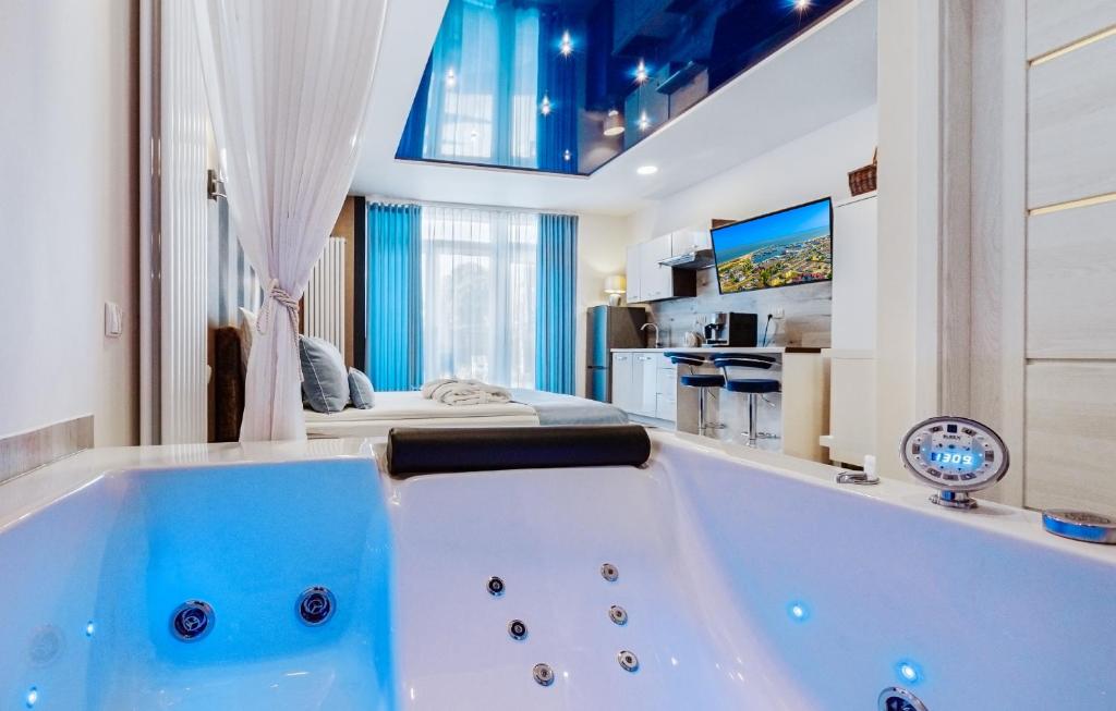 a large bath tub in a room with a bed at Elegante Apartments & Jacuzzi Władysławowo - Adults Only in Władysławowo