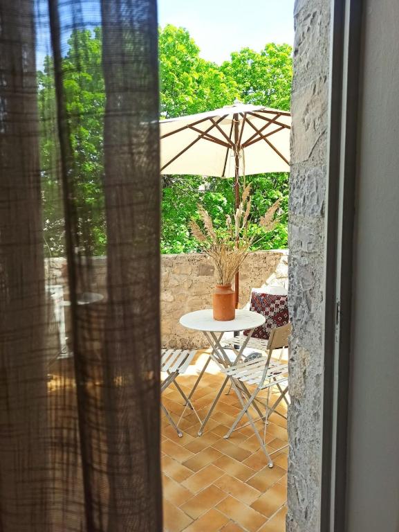 - une table et une chaise avec un parasol sur la terrasse dans l'établissement Les volets bleus, à Vaison-la-Romaine