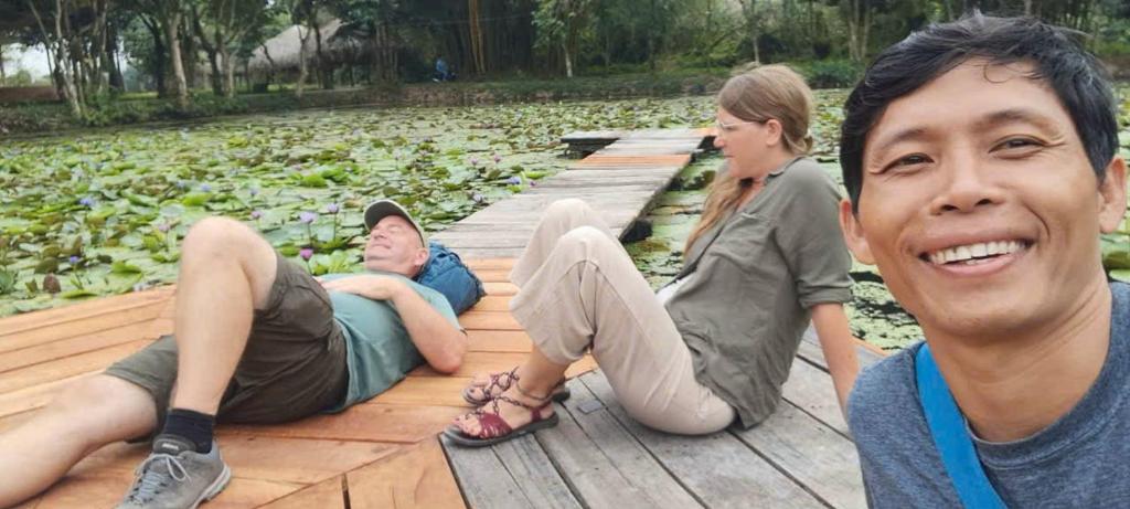 a group of people sitting on a wooden boardwalk at Mekong way homestay in Cai Lậy