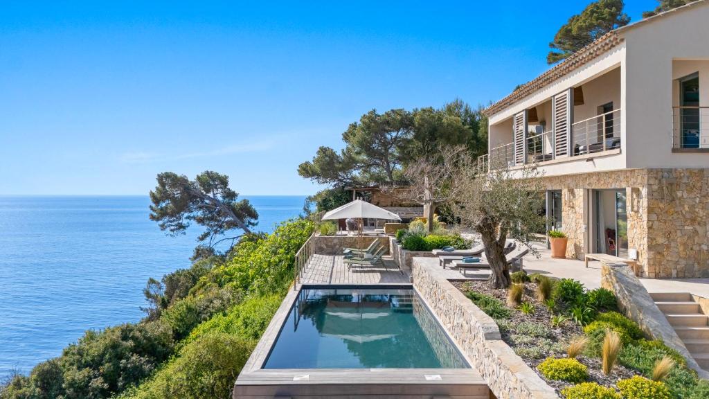 une maison avec une piscine à côté de l'océan dans l'établissement Les Falaises de Fabrégas, à La Seyne-sur-Mer