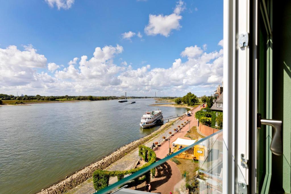 ein Boot auf einem Fluss mit Aussicht aus dem Fenster in der Unterkunft Fährmann im Häuschen am Rhein in Rees