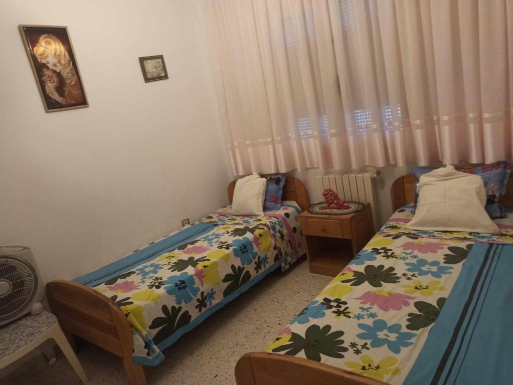 two twin beds in a room with curtains at Appartement Équipé et Confortable à Hammamet Nord in Hammamet Nord