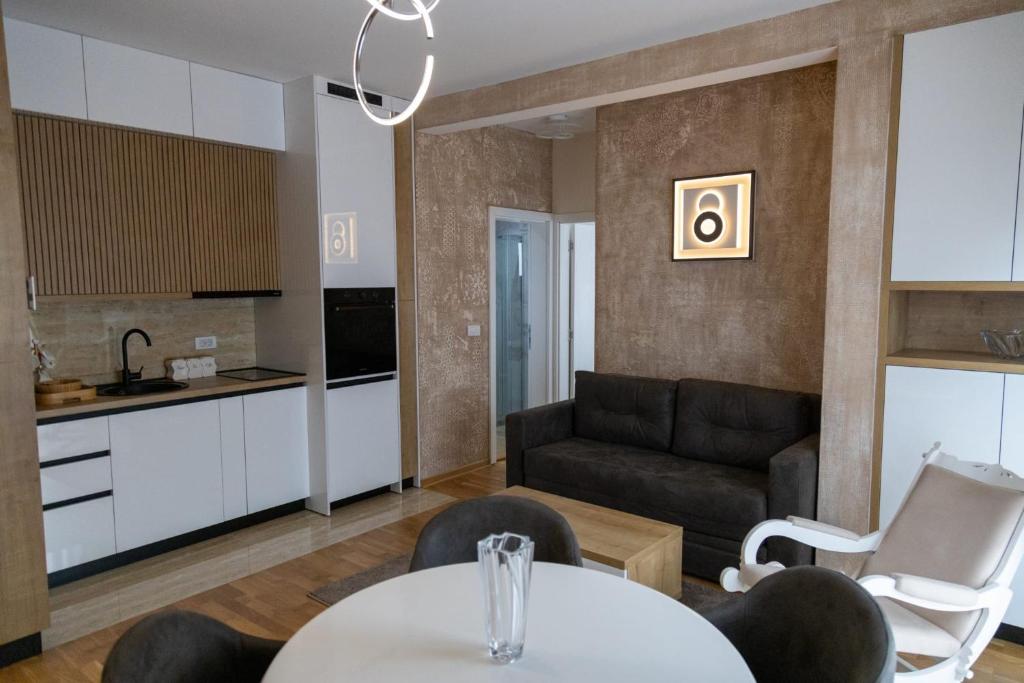 a kitchen and a living room with a table and chairs at Apartman Sunce Lux A in Vrnjačka Banja