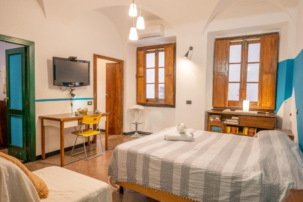 ein Schlafzimmer mit einem Bett, einem Schreibtisch und einem Fernseher in der Unterkunft Lovingenoa - Ducale - Old Stone in Genua