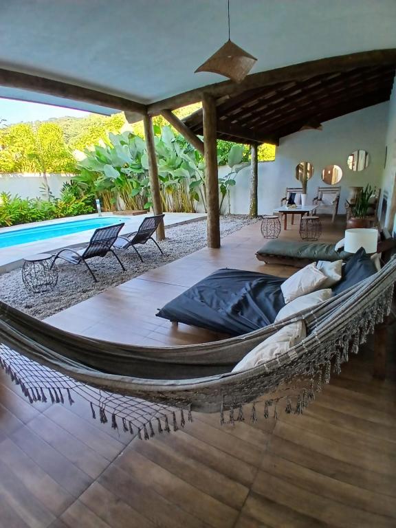 a hammock on a patio with a pool at Itamambuca Casa de Praia in Ubatuba