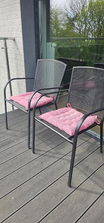 two chairs with pink cushions sitting on a porch at Apartament na Kolarskiej in Ostrów Mazowiecka