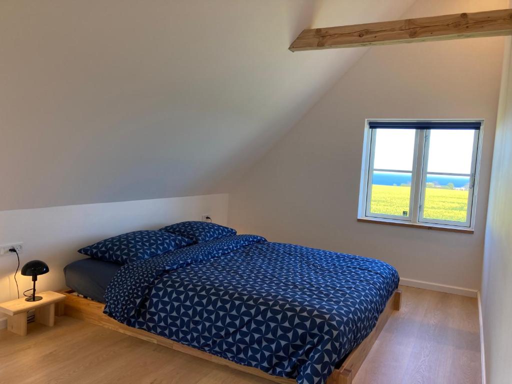 1 dormitorio con cama con edredón azul y ventana en Solhjem Bornholm - sea view - big garden, en Gudhjem