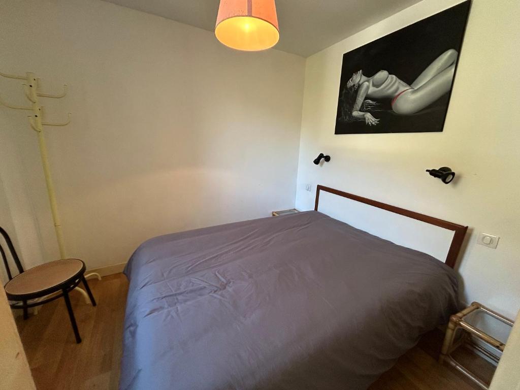 une chambre avec un lit, une lampe et une chaise dans l'établissement le desman, à La Celle-sous-Gouzon