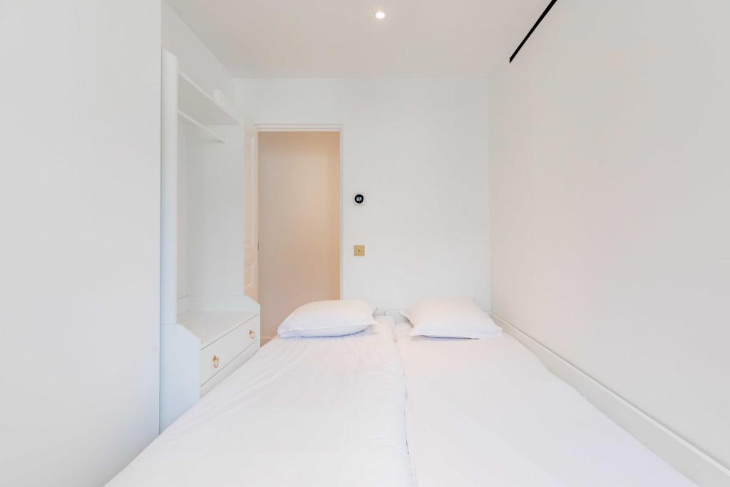 Cette chambre blanche comprend un lit. dans l'établissement Magnificent apartment - 3BR - 6P - Le Marais, à Paris