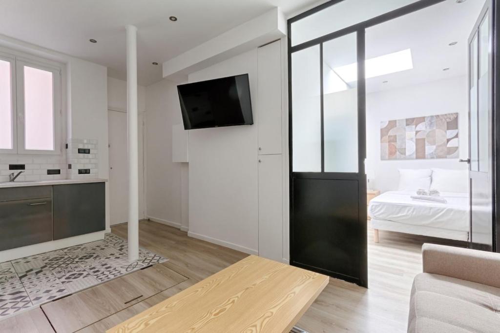 - un salon blanc avec une télévision et un lit dans l'établissement Daumesnil Gare de Lyon II Appartement Cosy 1BR, à La Celle-sous-Gouzon