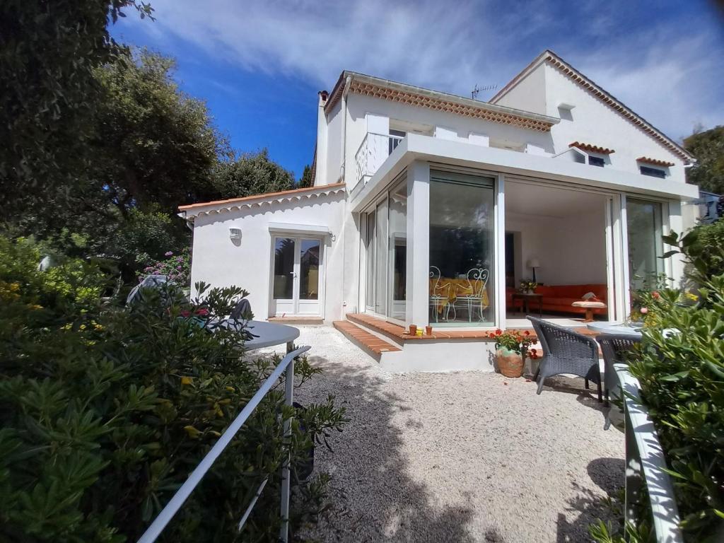 Cette maison blanche dispose d'une grande fenêtre et d'une terrasse. dans l'établissement Havre de paix, mer et jardin luxuriant, à Fréjus