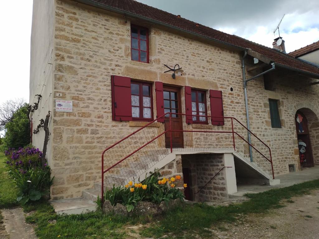 une maison en briques avec des fenêtres à volets rouges et des escaliers dans l'établissement gite chez jean de Vezelay, à Fontenay-près-Vézelay