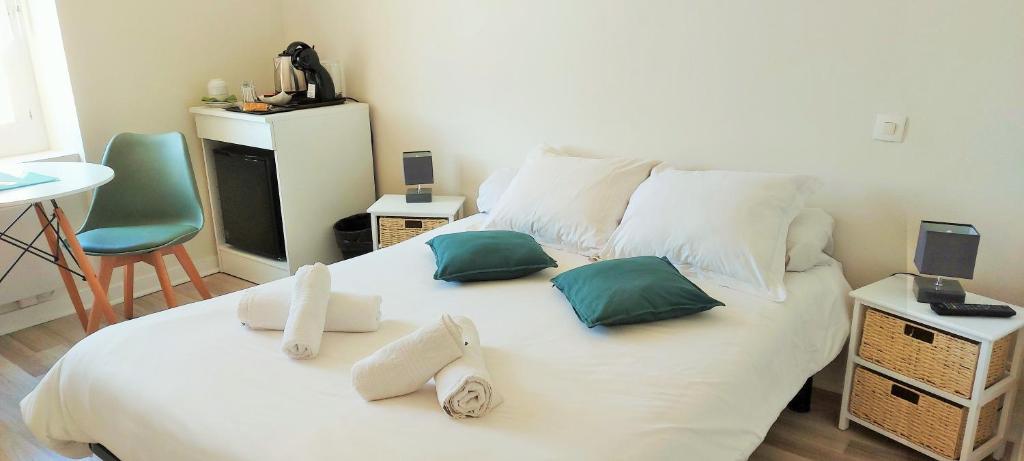 a bedroom with a large white bed with green pillows at Calme au bord de l'eau in Laroche-Saint-Cydroine