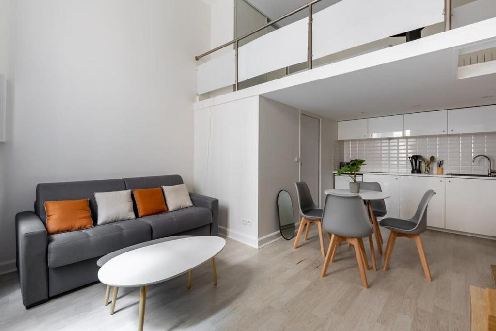 un salon avec un canapé, une table et des chaises dans l'établissement Appartement Duplex proche de l'Arc de Triomphe et Trocadero, à Paris