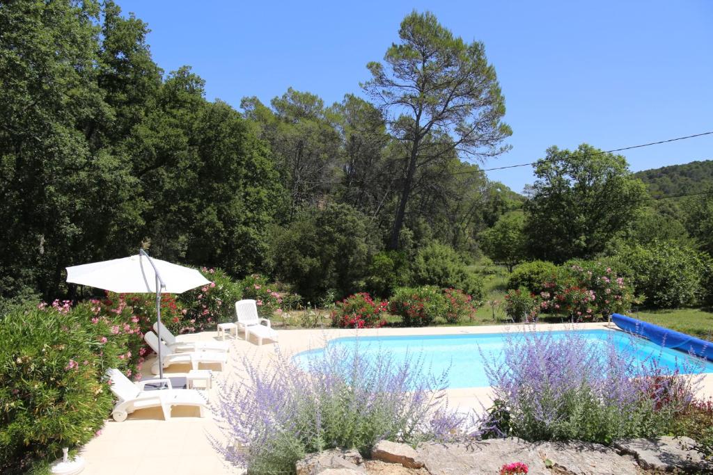 une piscine avec des chaises et un parasol dans l'établissement Villa les figuiers, à Lorgues