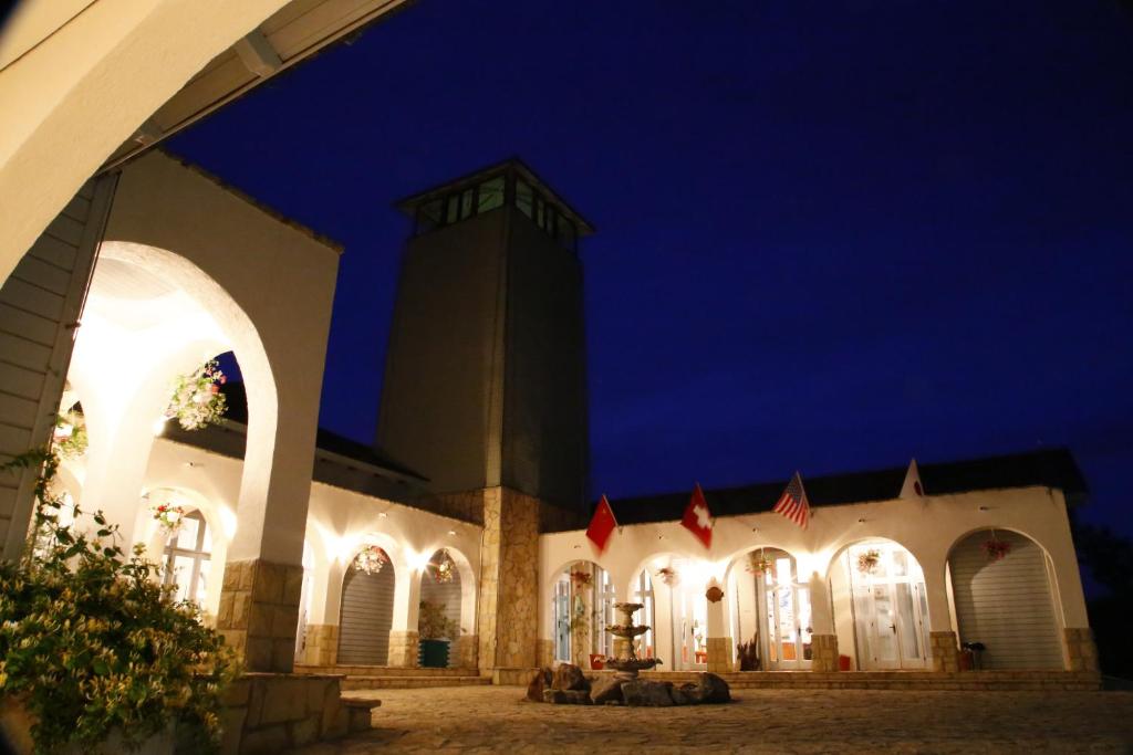 un edificio con una torre de reloj por la noche en Delta Resort Treetop by Eight Continents, en Tulcea