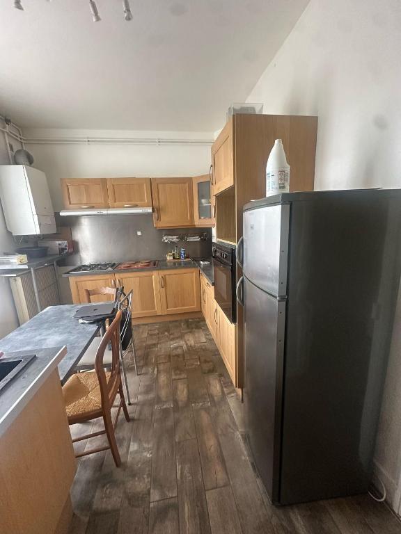 une cuisine avec un réfrigérateur en acier inoxydable et des armoires en bois dans l'établissement T4 chaleureux en plein centre, à Clermont-Ferrand