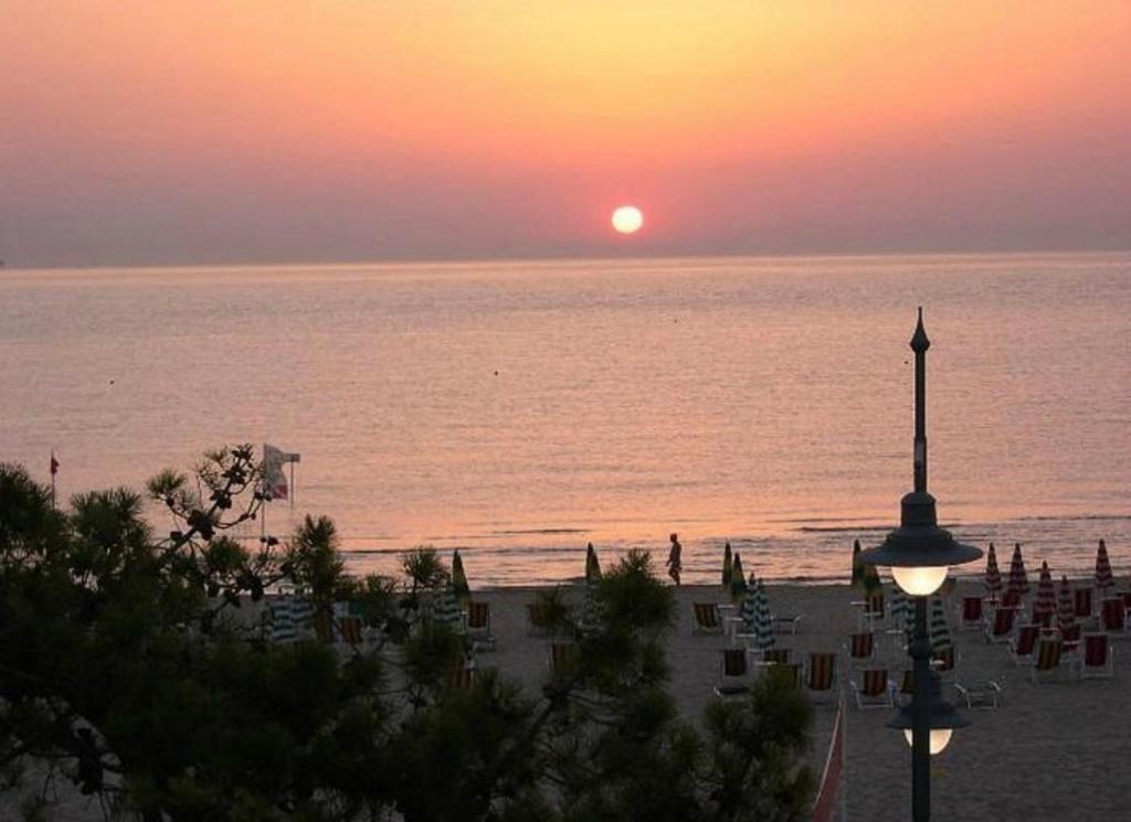 a sunset on the beach with the sun setting over the water at hotel cri cri - fronte spiaggia in Silvi Marina