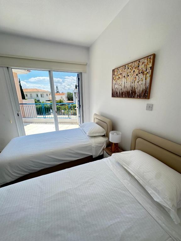 two beds in a bedroom with a large window at Two Bedroom Marsefino Amazing Townhouse-Apartment in Paphos City