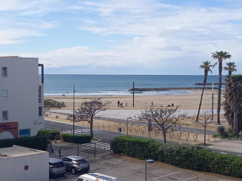 une vue sur une plage avec des palmiers et l'océan dans l'établissement T2 cabine 35m² + loggia à Sète, parking et vue sur la mer - FR-1-472-120, à Sète