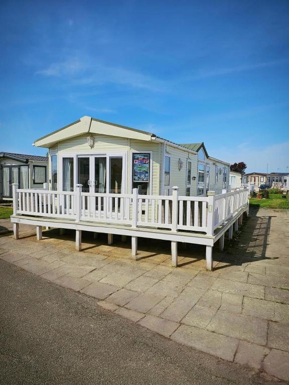 a white house with a porch and a white fence at Luxury lodge lyons robin hood in Rhyl