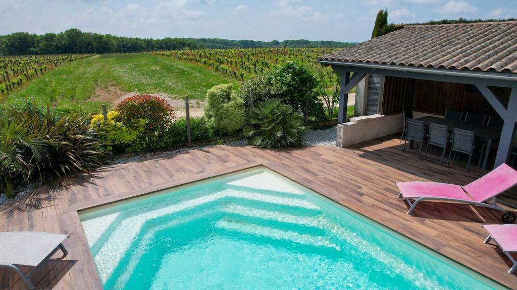 a swimming pool on a wooden deck next to a house at Maison au coeur des vignes in Puisseguin
