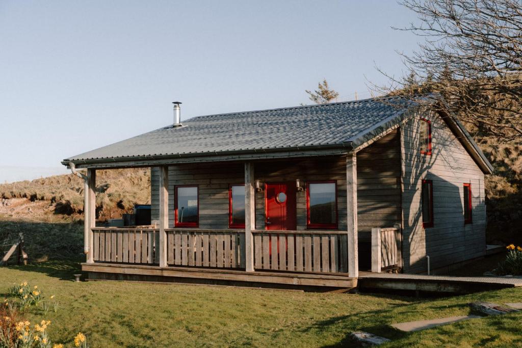 a log cabin with a porch and red doors at Cabin at Mackay's in Durness
