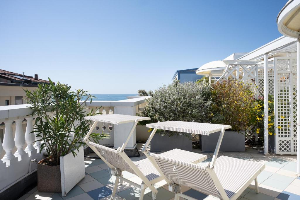 a patio with white chairs and tables on a balcony at Palace Hotel in Viareggio