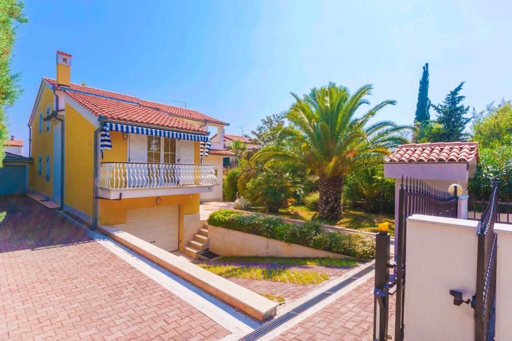 Casa amarilla con balcón y palmeras en Villa Nila, a charming villa just a short walk away from the beach, en Premantura