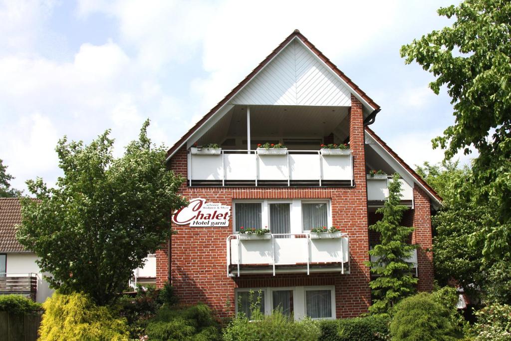 un edificio de ladrillo rojo con balcones blancos en Hotel Chalet en Bad Zwischenahn