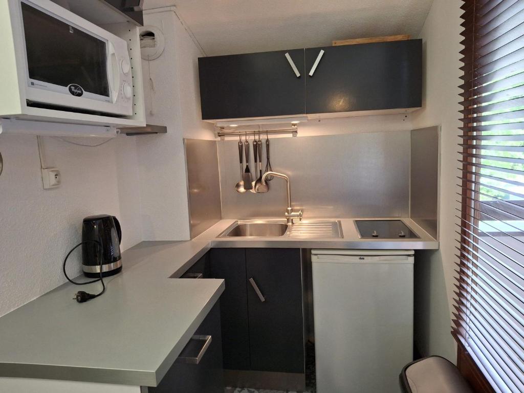 une petite cuisine avec un évier et un micro-ondes dans l'établissement Studio avec Balcon Exposé Est, Parking et WIFI Inclus - Brides-les-Bains - FR-1-512-186, à Brides-les-Bains