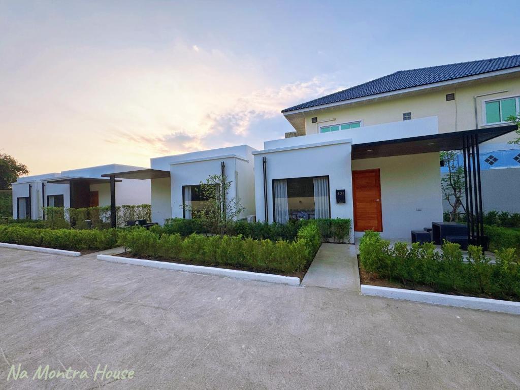 a large white house with a parking lot at มนต์จันทรา เฮ้าส์ in Khlong Lan