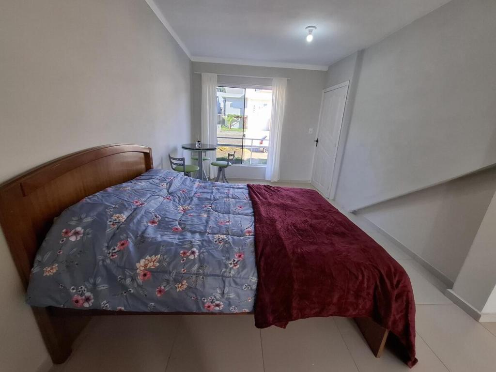 a bedroom with a bed with a blue comforter at Quarto com banheiro na cidade do Cristo in Encantado