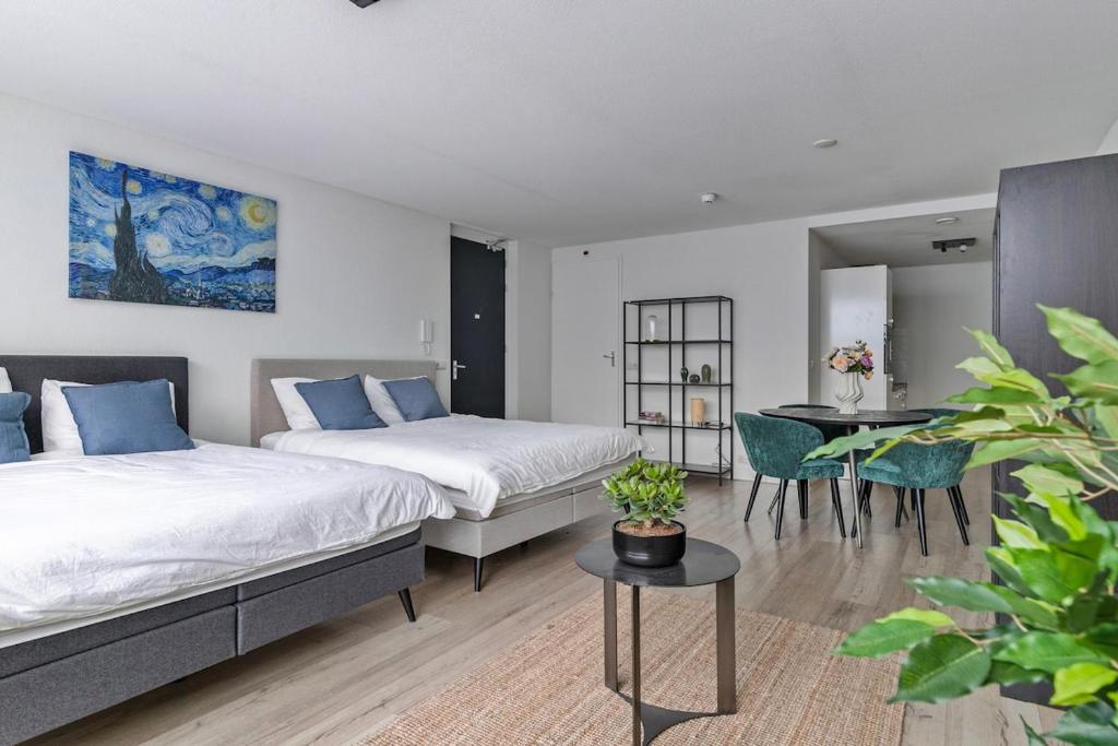 a bedroom with two beds and a table and a dining room at Central and light apartment in Rotterdam
