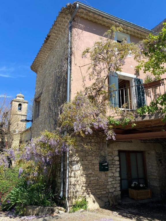 - un vieux bâtiment en pierre avec des fleurs violettes dans l'établissement La Maison Rose I Maison de village familiale, à Lagnes