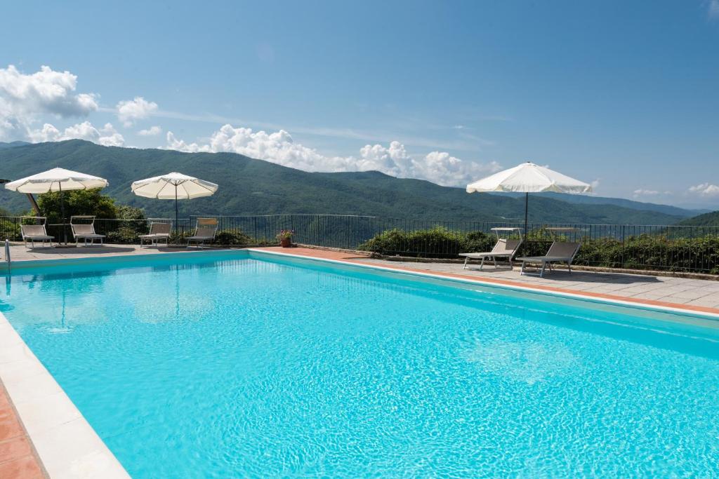 a large swimming pool with chairs and umbrellas at Universal Harmony - Nibbio in Dicomano