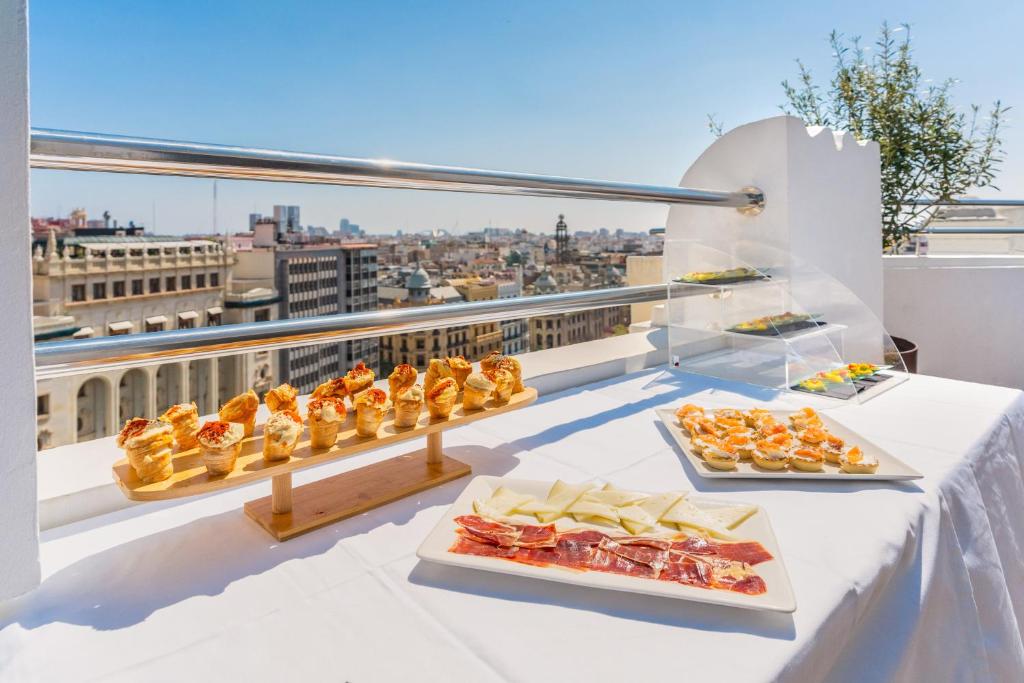 a table with several plates of food on a balcony at Melia Plaza Valencia in Valencia