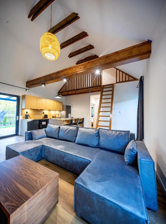 a living room with a blue couch and a kitchen at Wilcza Stodoła 2 in Uście