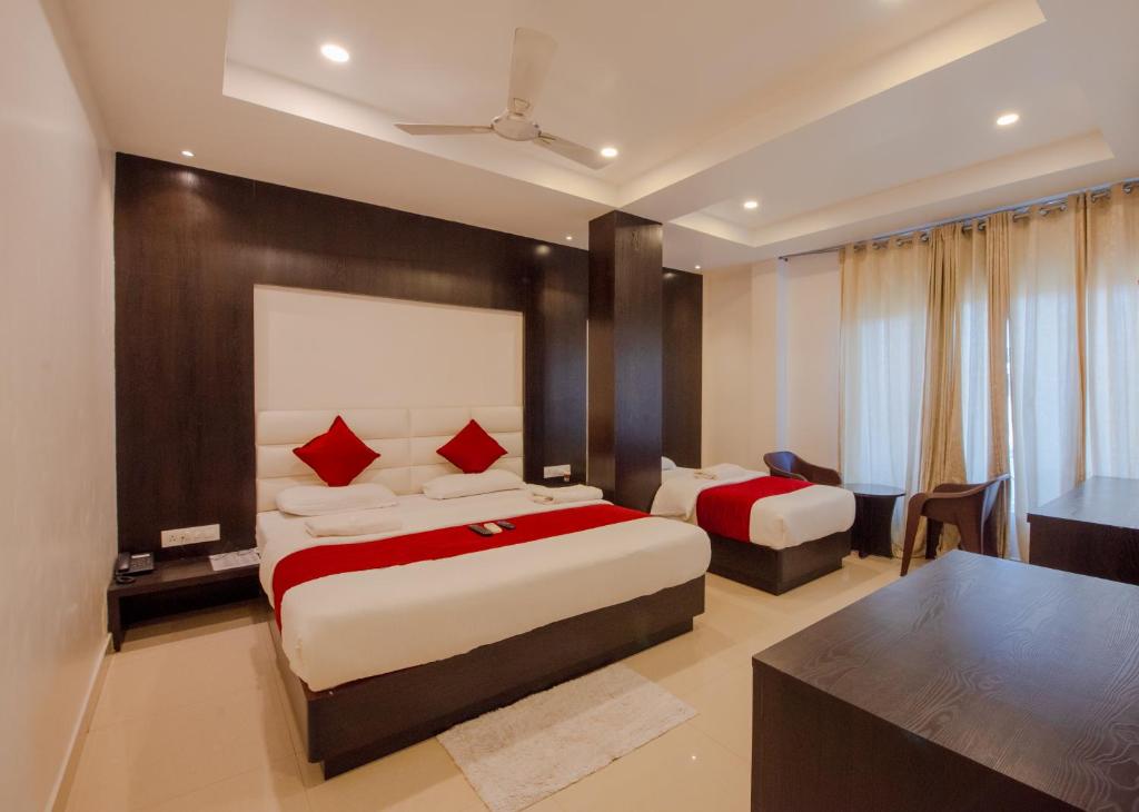 a hotel room with two beds and a desk at Hotel Horizon Hues in Port Blair
