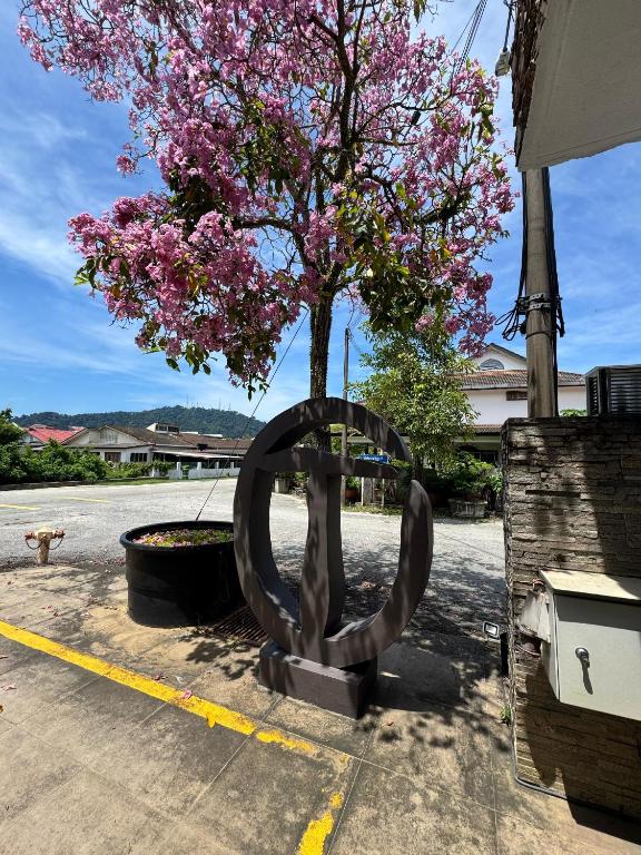 a metal sculpture next to a tree with pink flowers at Tropical villa in Kuantan
